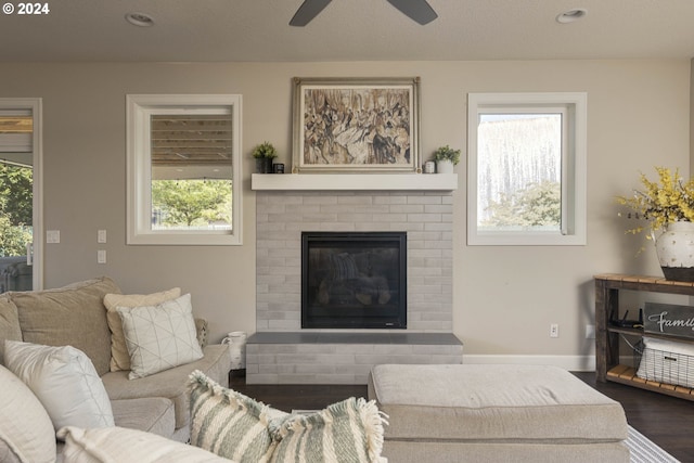 living room with a brick fireplace, a textured ceiling, a healthy amount of sunlight, and dark hardwood / wood-style flooring