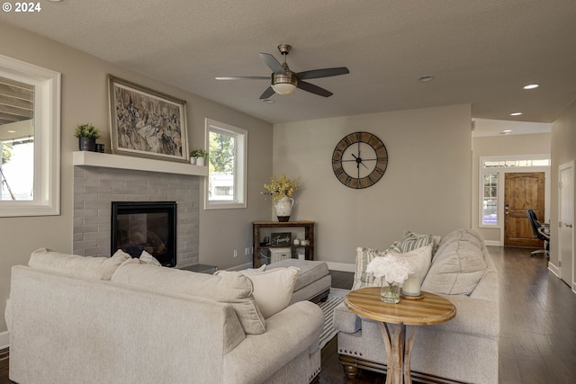 living room with dark hardwood / wood-style floors, a textured ceiling, a fireplace, and ceiling fan