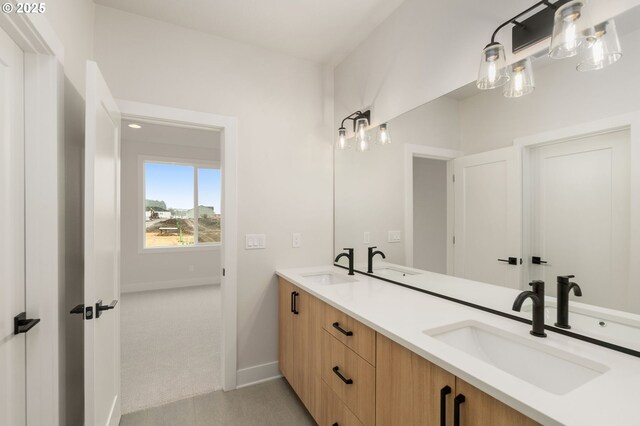 bathroom with double vanity, a sink, and baseboards