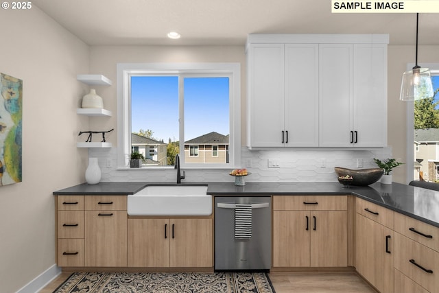 kitchen with light brown cabinetry, open shelves, a sink, dark countertops, and dishwasher