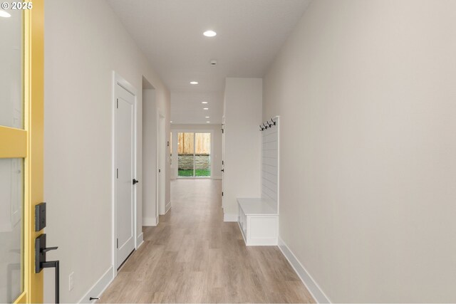 hall featuring baseboards, recessed lighting, and light wood finished floors