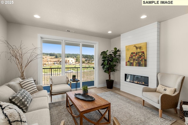 living area featuring light wood-style flooring, recessed lighting, and visible vents