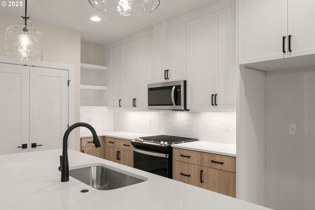 kitchen featuring open shelves, appliances with stainless steel finishes, light countertops, backsplash, and a sink
