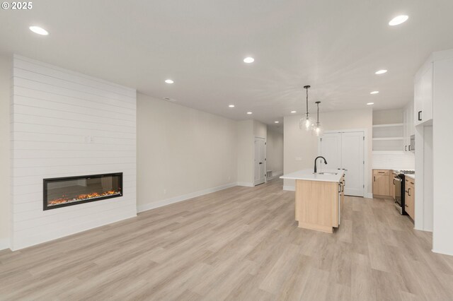 kitchen featuring recessed lighting, light wood-style flooring, open floor plan, and a fireplace