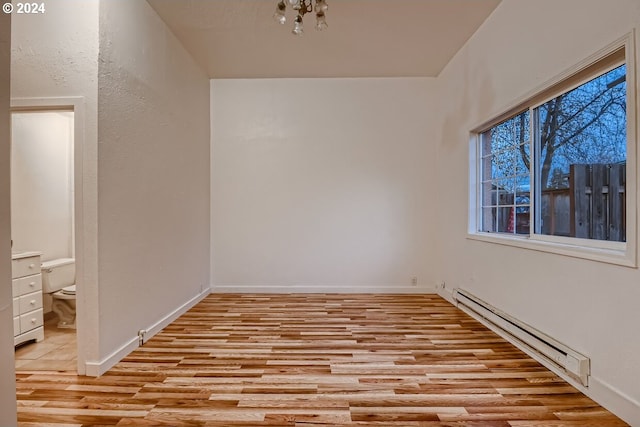 empty room with light hardwood / wood-style floors and baseboard heating