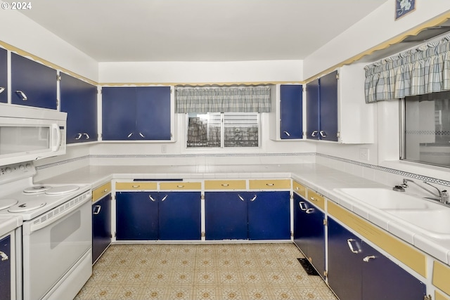 kitchen with blue cabinets, sink, and white appliances