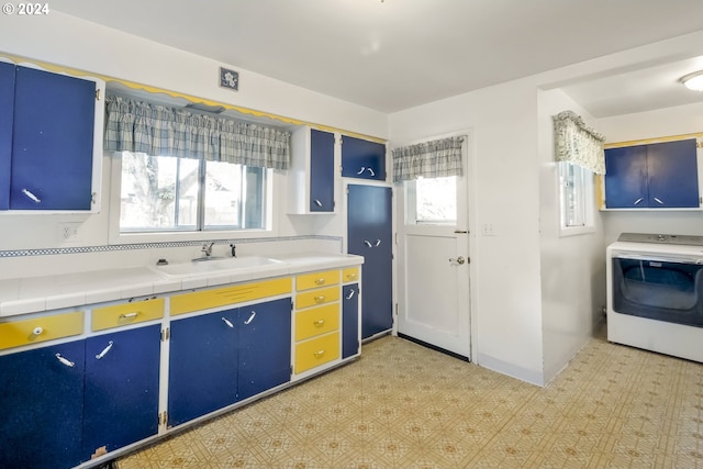 kitchen featuring a healthy amount of sunlight, blue cabinetry, sink, and washer / dryer