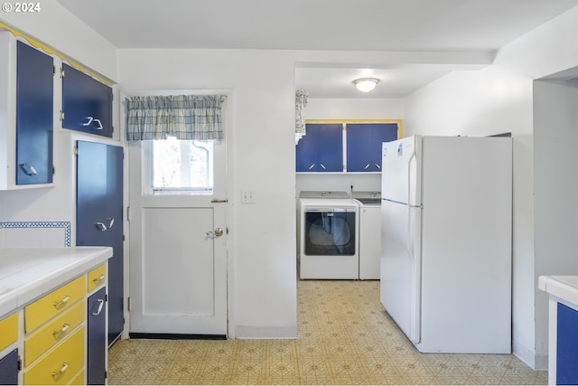 kitchen featuring washing machine and dryer, blue cabinets, and white fridge