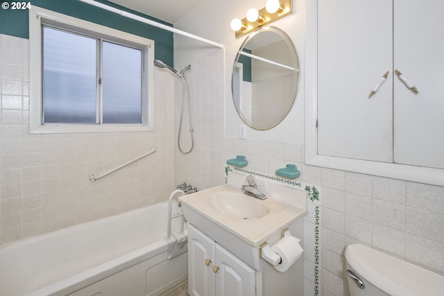 full bathroom with tile walls, tiled shower / bath, vanity, and toilet