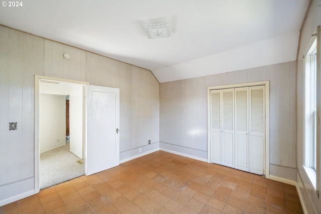 unfurnished bedroom featuring lofted ceiling, a closet, and light colored carpet