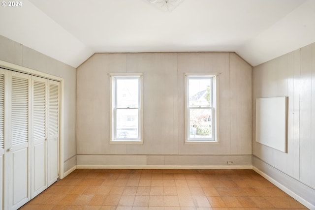 additional living space with vaulted ceiling and wooden walls