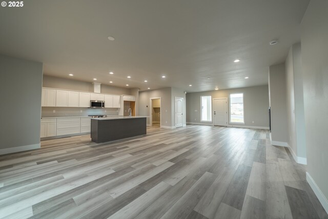 kitchen featuring white cabinetry, a center island with sink, and light hardwood / wood-style flooring