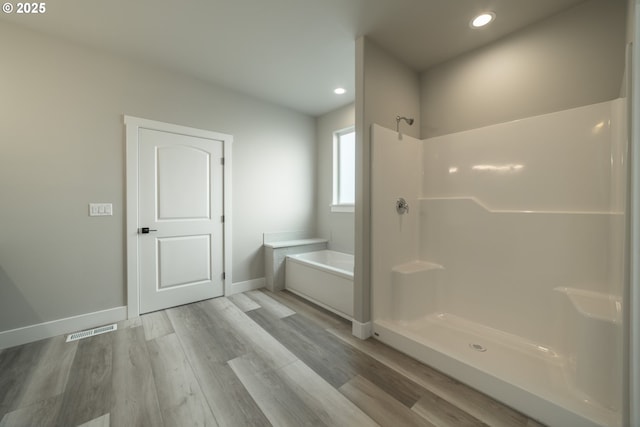 bathroom with hardwood / wood-style flooring and shower with separate bathtub