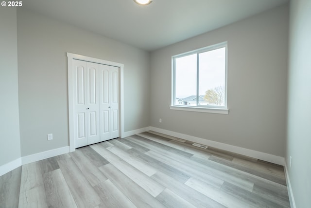 unfurnished bedroom with a closet and light wood-type flooring