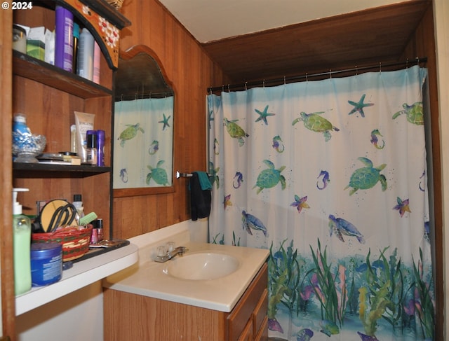 bathroom featuring vanity, curtained shower, and wood walls