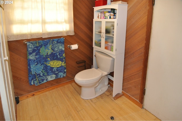 bathroom featuring hardwood / wood-style flooring, wooden walls, and toilet