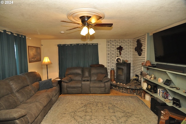 living room with hardwood / wood-style flooring, ceiling fan, a textured ceiling, and a wood stove