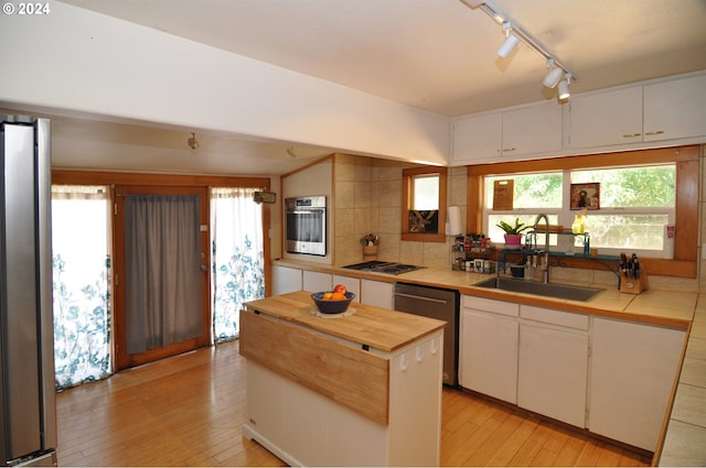 kitchen featuring sink, a wealth of natural light, stainless steel appliances, light hardwood / wood-style floors, and white cabinets