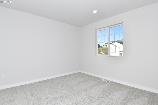 carpeted spare room with visible vents and baseboards