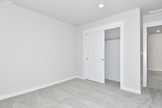 unfurnished bedroom with recessed lighting, a closet, baseboards, and light colored carpet