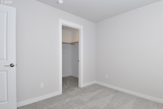 unfurnished bedroom featuring a spacious closet, a closet, baseboards, and carpet