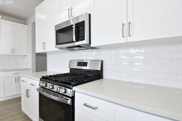 kitchen featuring decorative backsplash, light countertops, white cabinets, and appliances with stainless steel finishes