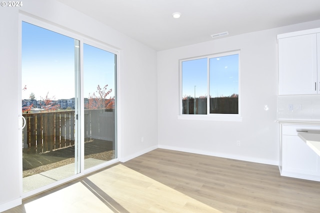 empty room with visible vents, light wood-style floors, and baseboards