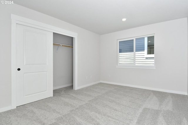 unfurnished bedroom with light colored carpet and a closet