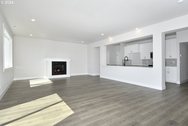 unfurnished living room featuring dark hardwood / wood-style floors and sink