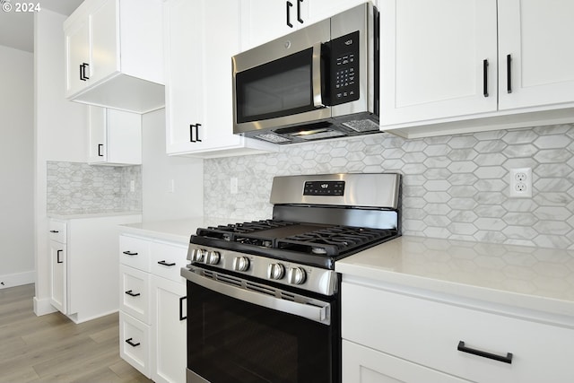 kitchen featuring decorative backsplash, white cabinets, stainless steel appliances, and light hardwood / wood-style floors