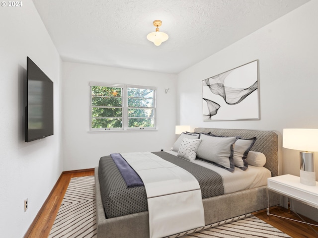 bedroom with a textured ceiling and light wood-type flooring