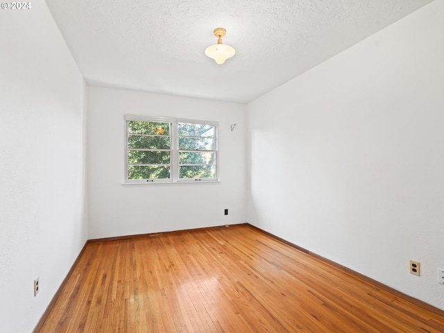 empty room with hardwood / wood-style floors and a textured ceiling