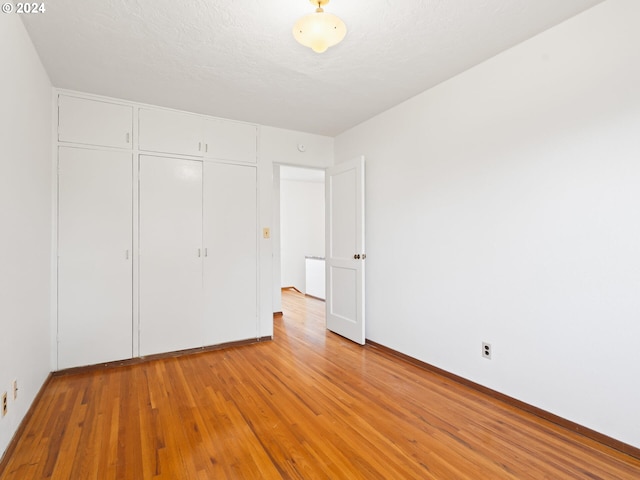 unfurnished bedroom with a closet, light hardwood / wood-style floors, and a textured ceiling