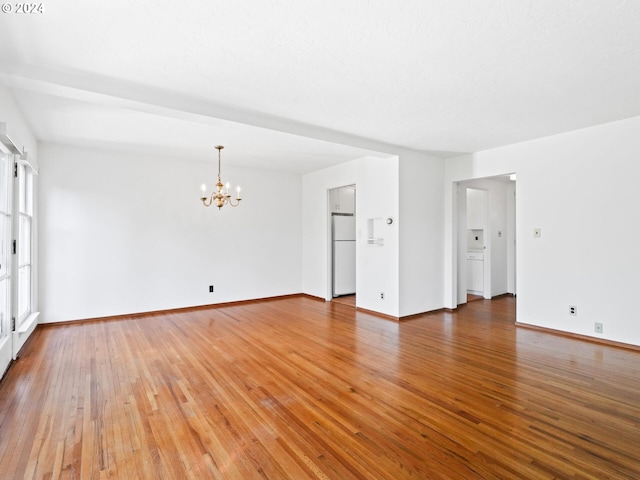 unfurnished room with wood-type flooring and an inviting chandelier