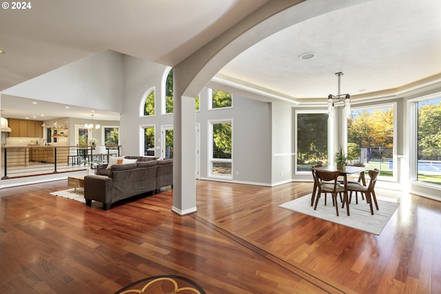 living room featuring a healthy amount of sunlight, wood-type flooring, and a chandelier