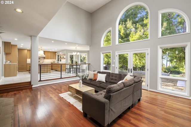 living room with an inviting chandelier, hardwood / wood-style floors, a healthy amount of sunlight, and a high ceiling