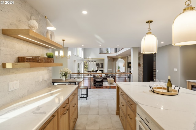 kitchen with light stone countertops, tile walls, light tile patterned floors, and decorative light fixtures