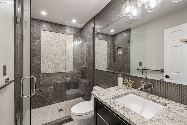 bathroom with toilet, backsplash, tile walls, vanity, and walk in shower