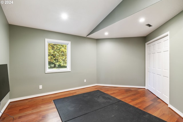 workout room with hardwood / wood-style floors and vaulted ceiling