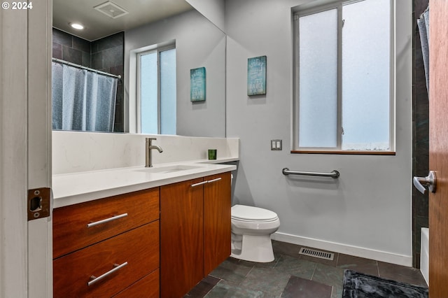 bathroom with toilet, vanity, and walk in shower