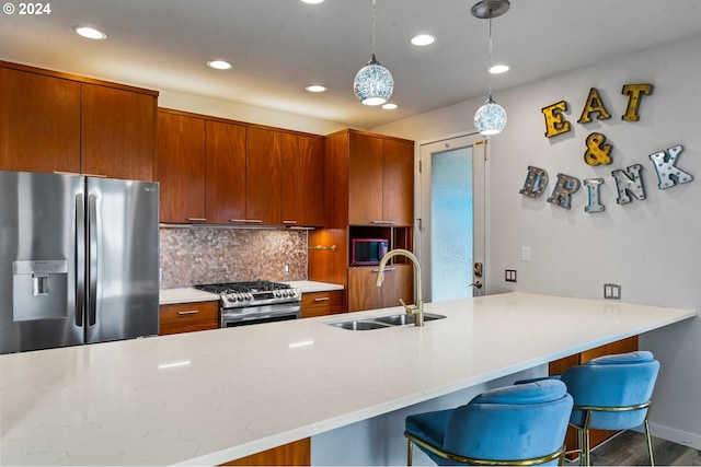 kitchen with tasteful backsplash, sink, hanging light fixtures, a breakfast bar area, and stainless steel appliances