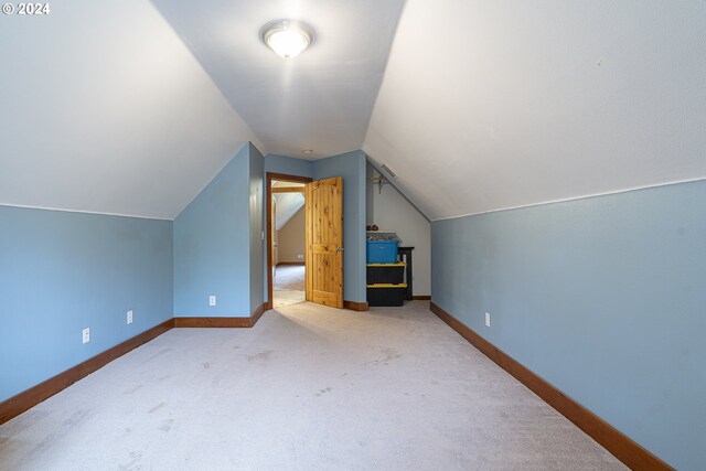 carpeted home office featuring vaulted ceiling