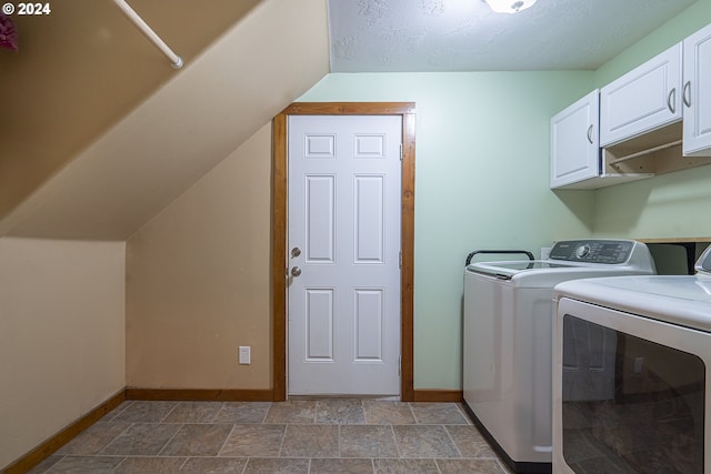 washroom with a textured ceiling, cabinets, and washing machine and clothes dryer