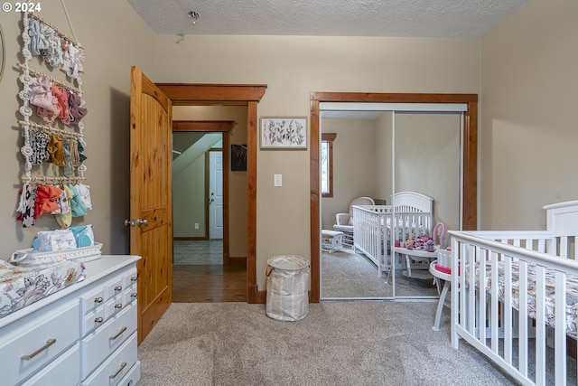 carpeted bedroom featuring a crib and a textured ceiling