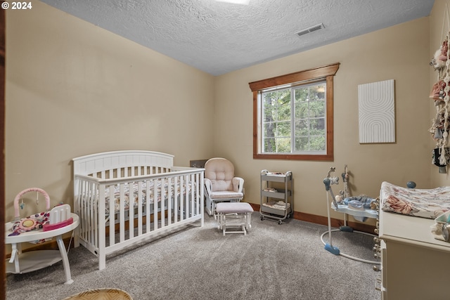 bedroom featuring a crib, carpet floors, and a textured ceiling