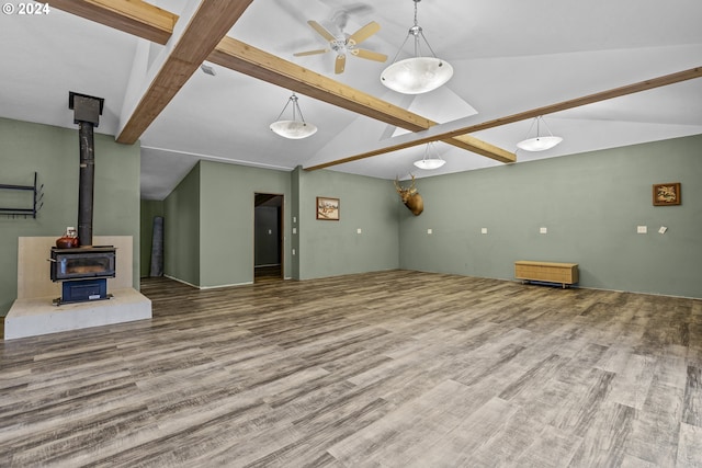 unfurnished living room featuring wood-type flooring, lofted ceiling with beams, and a wood stove