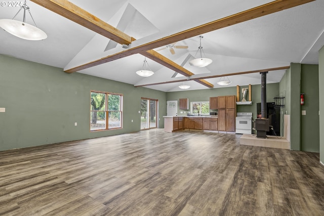 unfurnished living room featuring hardwood / wood-style flooring, vaulted ceiling with beams, and a wood stove