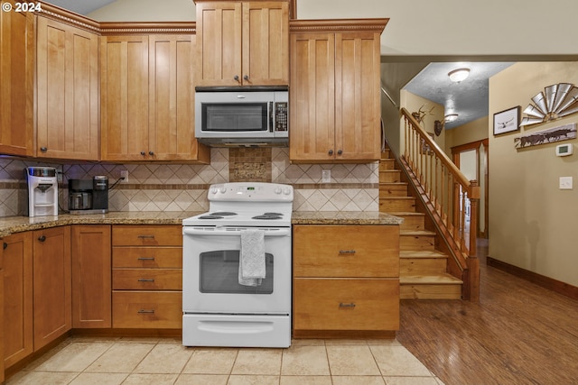 kitchen with tasteful backsplash, electric range, light hardwood / wood-style floors, and light stone counters