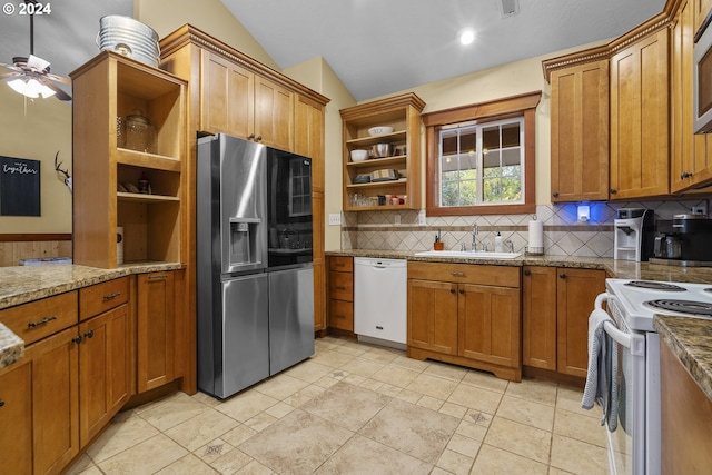 kitchen with sink, light stone counters, tasteful backsplash, vaulted ceiling, and stainless steel appliances