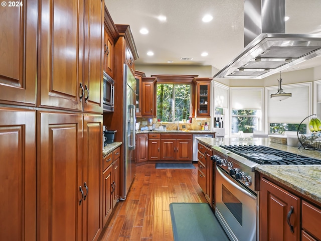 kitchen featuring pendant lighting, sink, high end appliances, island exhaust hood, and dark wood-type flooring